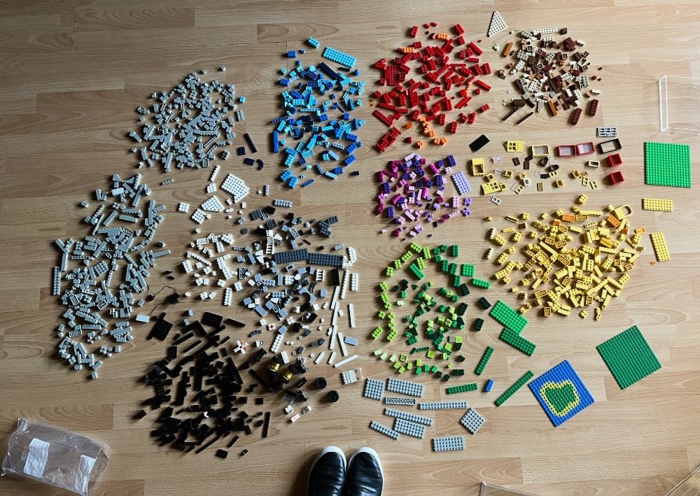 a photo taken from the top looking down at the floor, showing hundreds of LEGO bricks organized by color