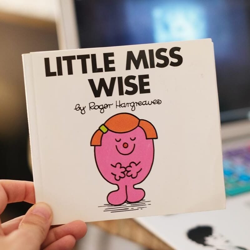 a photo of a hand holding up a copy of the book LITTLE MISS WISE by Roger Hargreaves