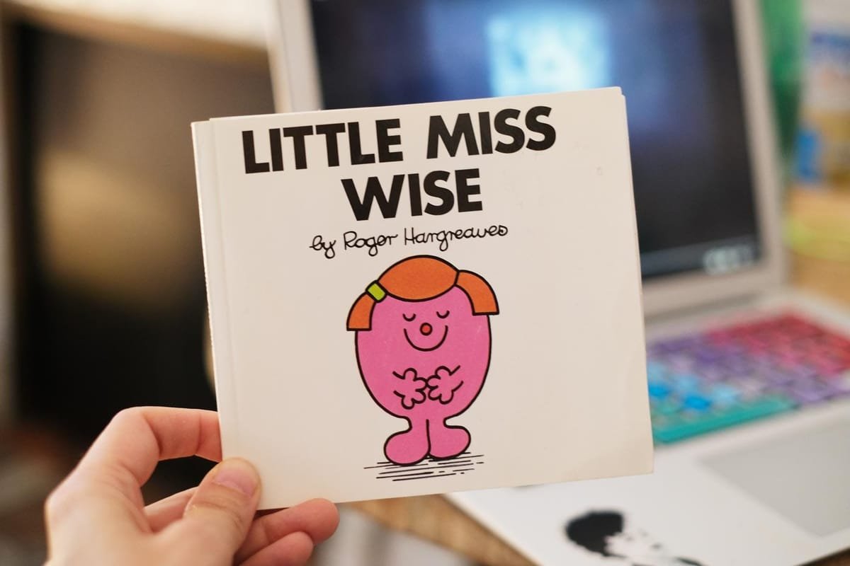 a photo of a hand holding up a copy of the book LITTLE MISS WISE by Roger Hargreaves