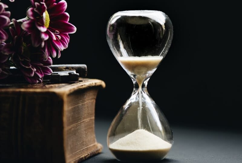 a photo of an hourglass with sand falling down set against a dark backdrop