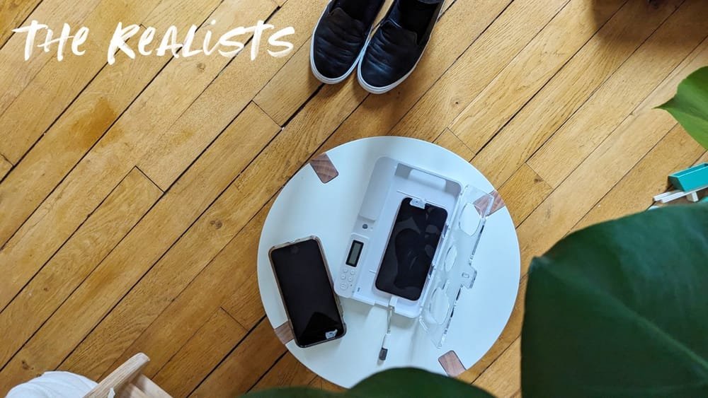 a photo showing two phones on a small round white table: my main phone on the left and a second phone on the right inside a box, with a dongle